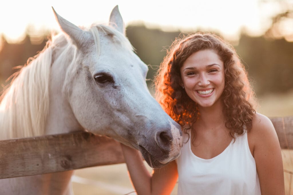 Young girlm smiling next to a horse