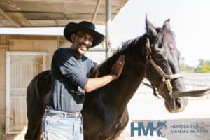 Man standing next to a horse and smiling at the viewer
