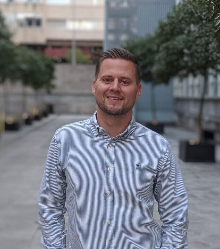 Headshot of Tyler standing in a tree lined plaza