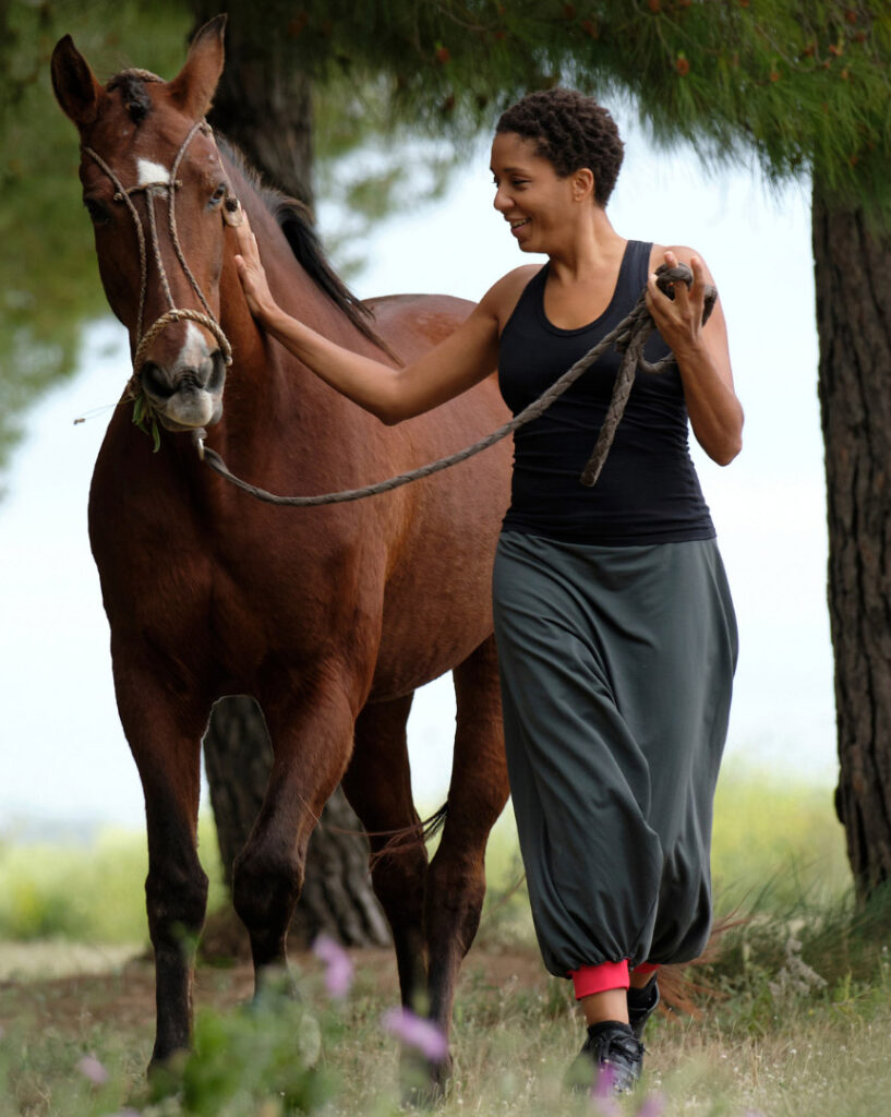 A smiling woman walking with a horse